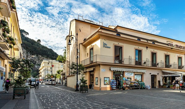 Una calle con edificios, un café y una montaña al fondo.