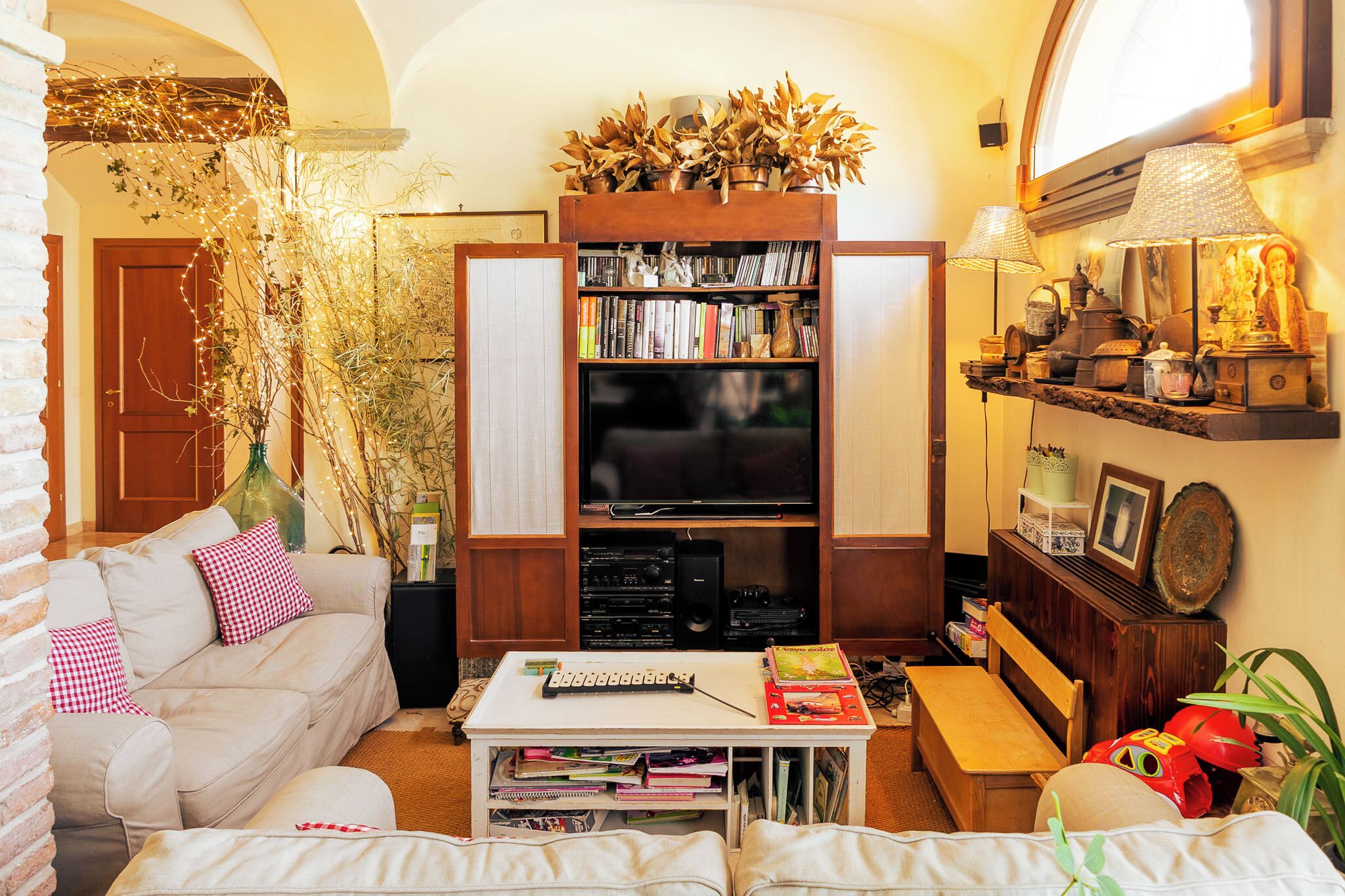 Un salon confortable avec un canapé, une table basse sur laquelle sont posés des livres, une bibliothèque et un téléviseur.