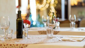 Una mesa de comedor servida con copas de vino, una botella y una rosa.