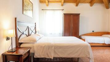 A bedroom with a wooden bed, a nightstand, a wardrobe, and a window with curtains.