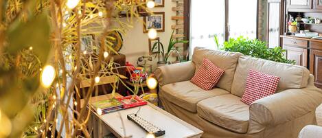A cozy living room with a beige sofa, a small white coffee table, and a bookshelf filled with books and toys.
