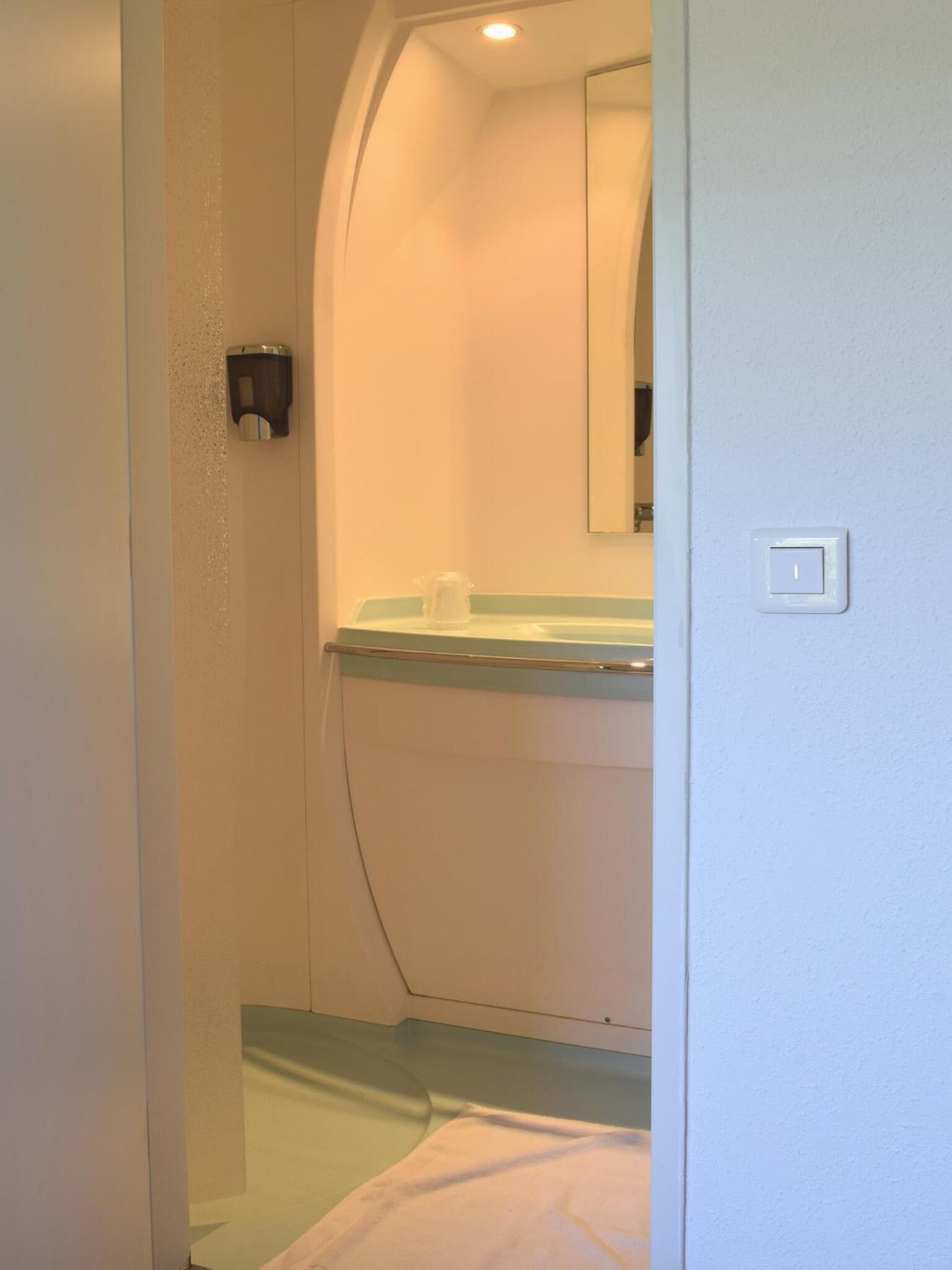 A bathroom with a toilet, sink, and mirror.
