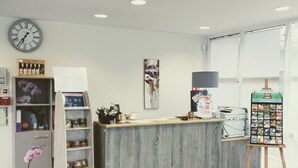 Un comptoir d’accueil avec une horloge, un tableau représentant des fleurs et un panneau affichant le menu.