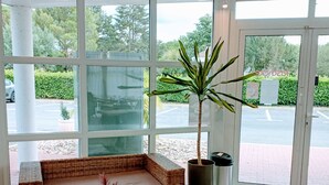 Un intérieur moderne avec un canapé en osier, une table en marbre et une grande plante en pot.