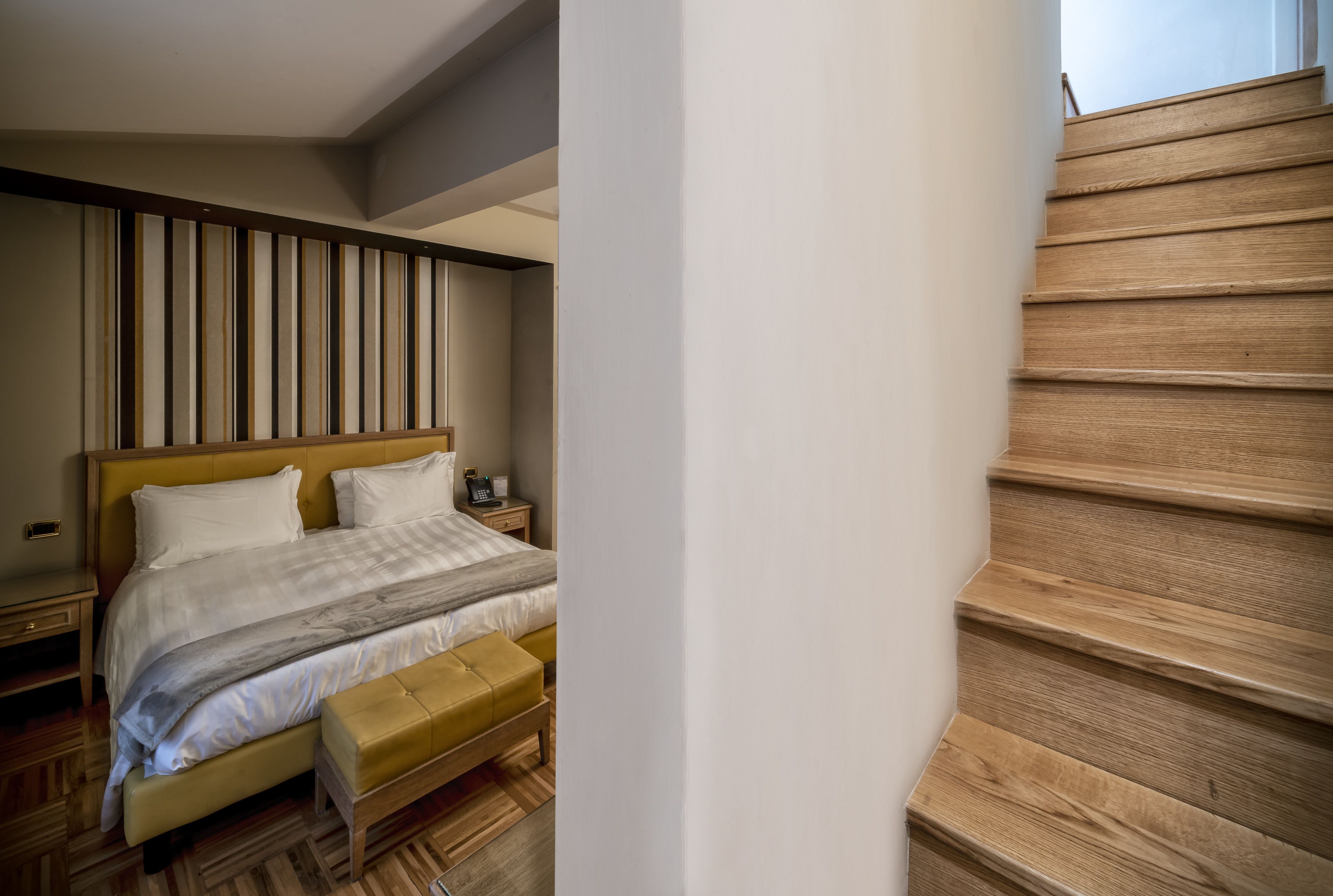 Un dormitorio con cama, mesita de noche y una escalera de madera.