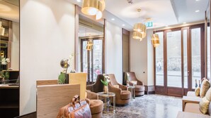 En moderne lobby med siddeområder, en receptionsdisk og store vinduer.