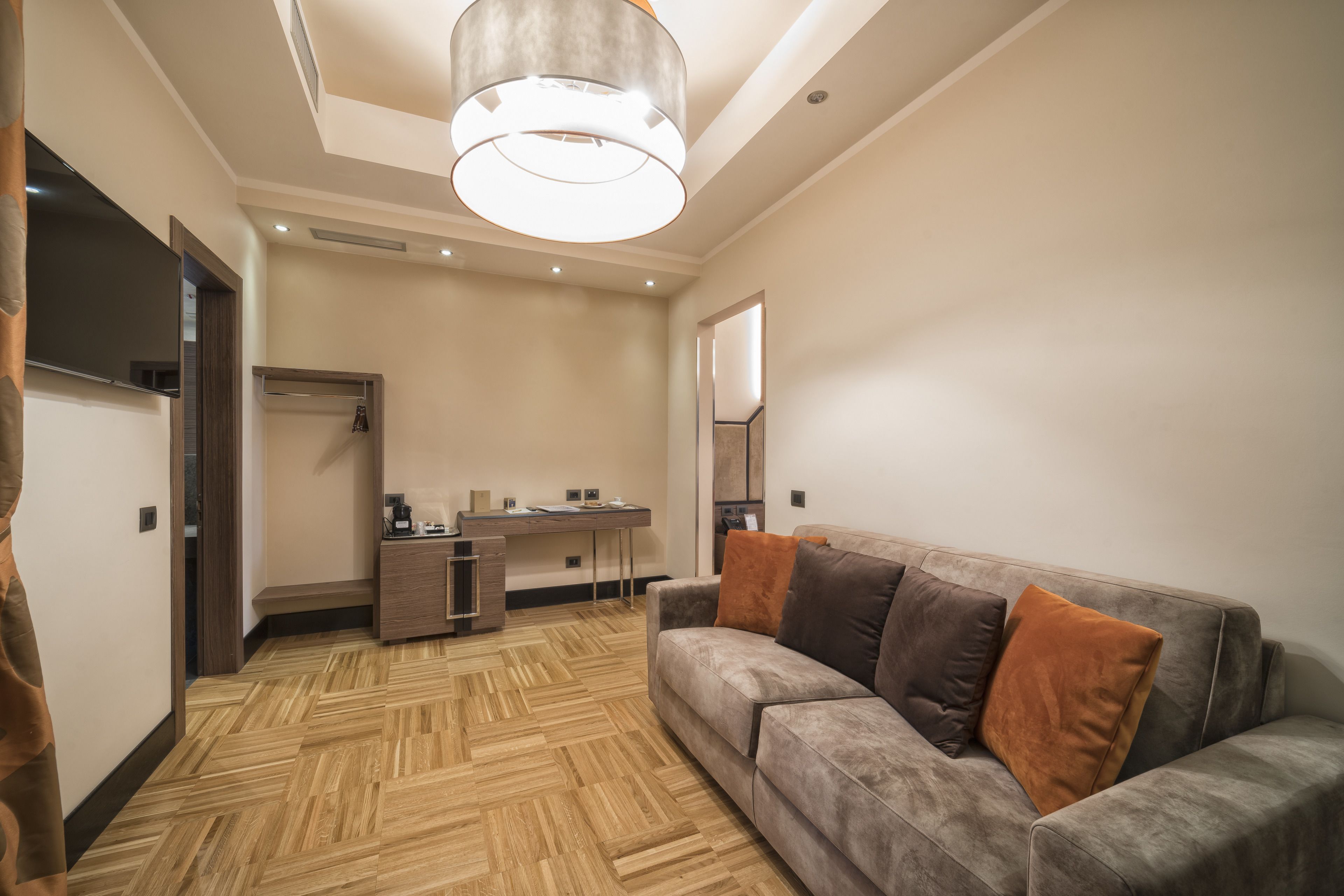 Une chambre d’hôtel moderne, équipée d’un canapé, d’un bureau et d’un grand miroir.
