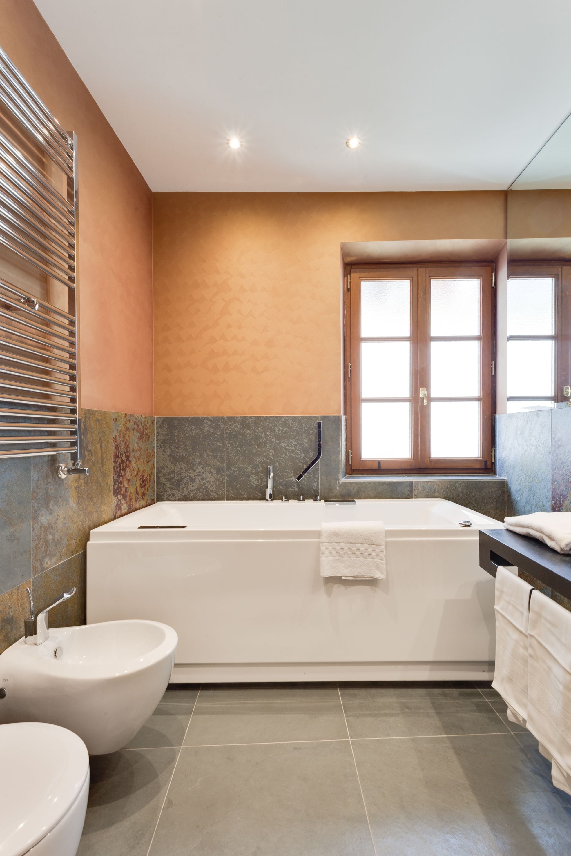 A modern bathroom with a freestanding bathtub, a bidet, and a vanity with a mirror.