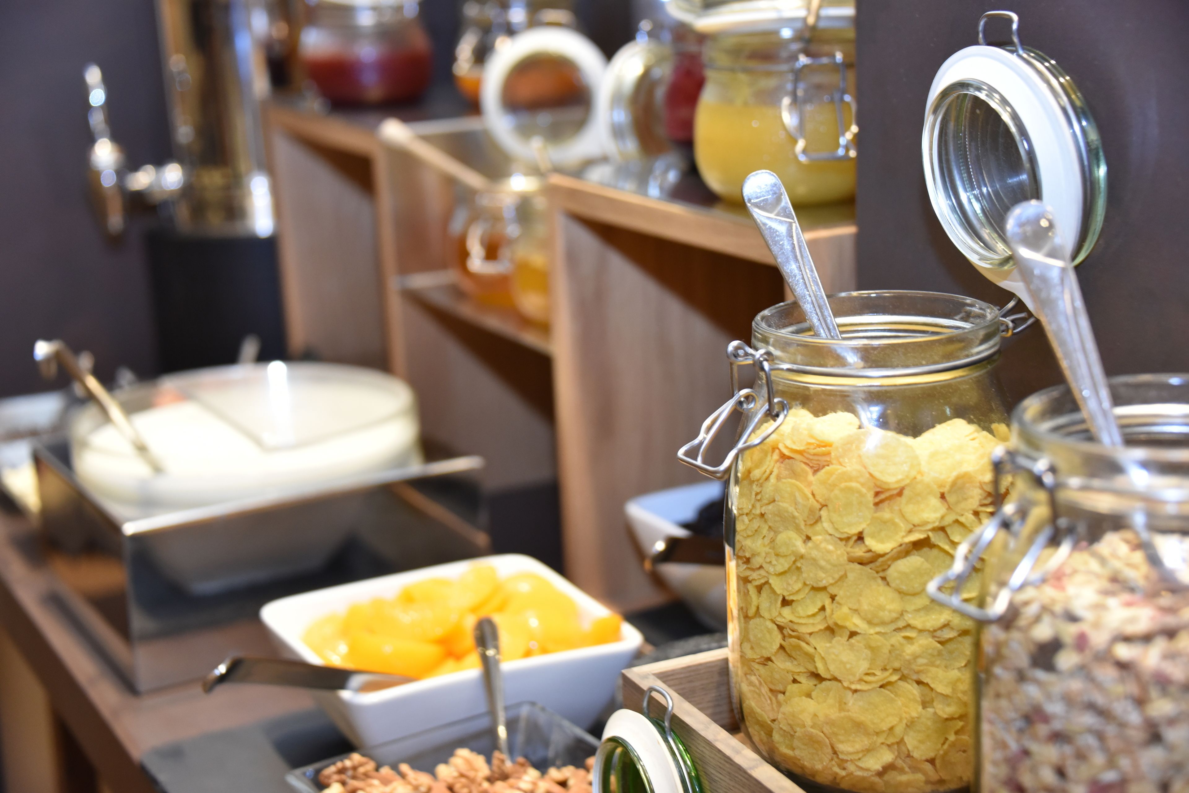 Un bufé con diferentes opciones de comida, como cereales, frutas y frutos secos.