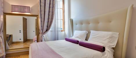 A neatly arranged bedroom with a large bed, a bedside table, and a mirror.