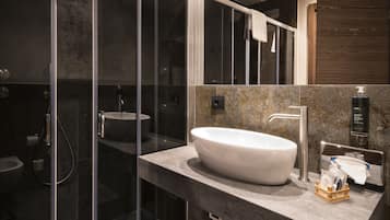 Un bagno moderno con un'ampia cabina doccia in vetro, un lavabo sospeso e uno specchio sopra il lavabo.