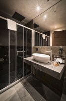 Un bagno moderno con un'ampia cabina doccia in vetro, un lavabo sospeso e uno specchio sopra il lavabo.