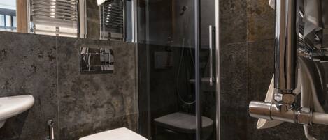 A modern bathroom with a glass-enclosed shower, a toilet, and a sink.