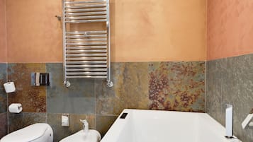 Een moderne badkamer met een groot bad, een apart toilet en een bidet.
