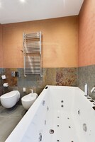 Een moderne badkamer met een groot bad, een apart toilet en een bidet.
