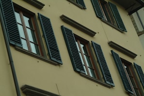 A building facade with multiple windows, each featuring dark shutters. - Solo Experience Hotel (Florence)