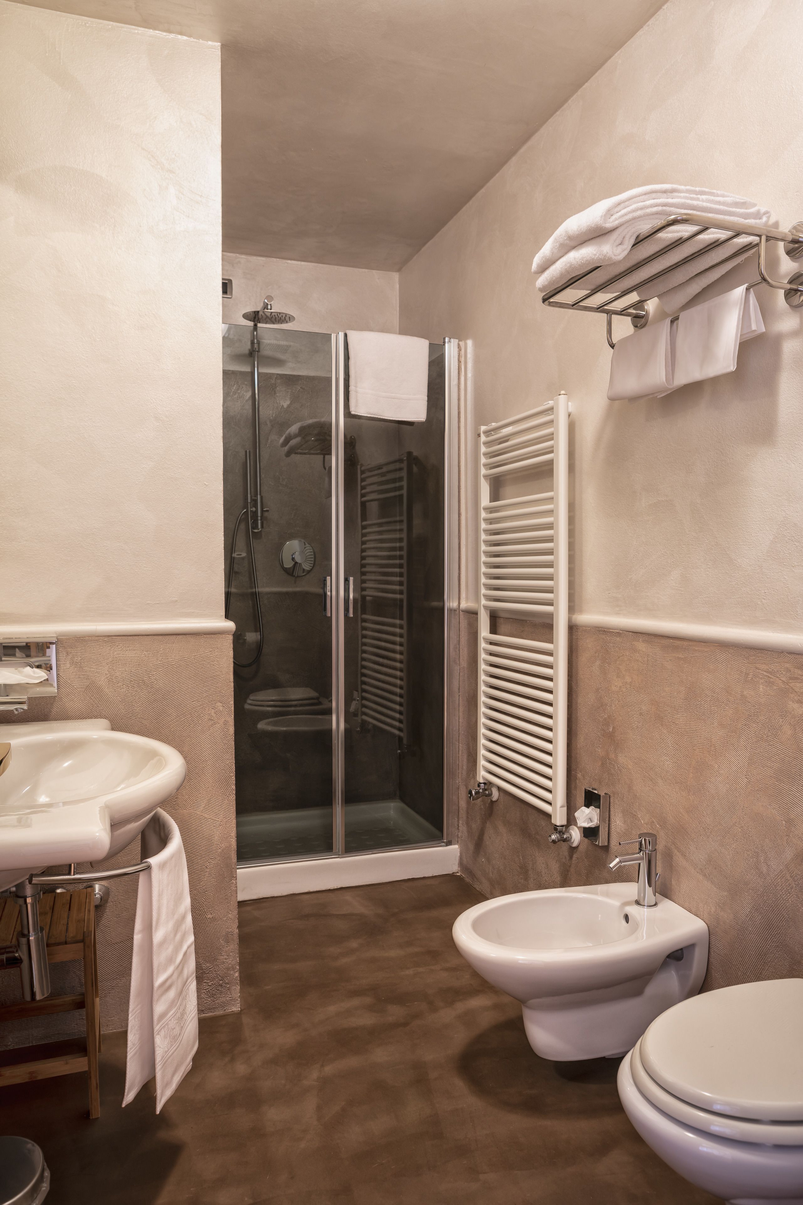A bathroom with a shower, bidet, sink, and toilet.