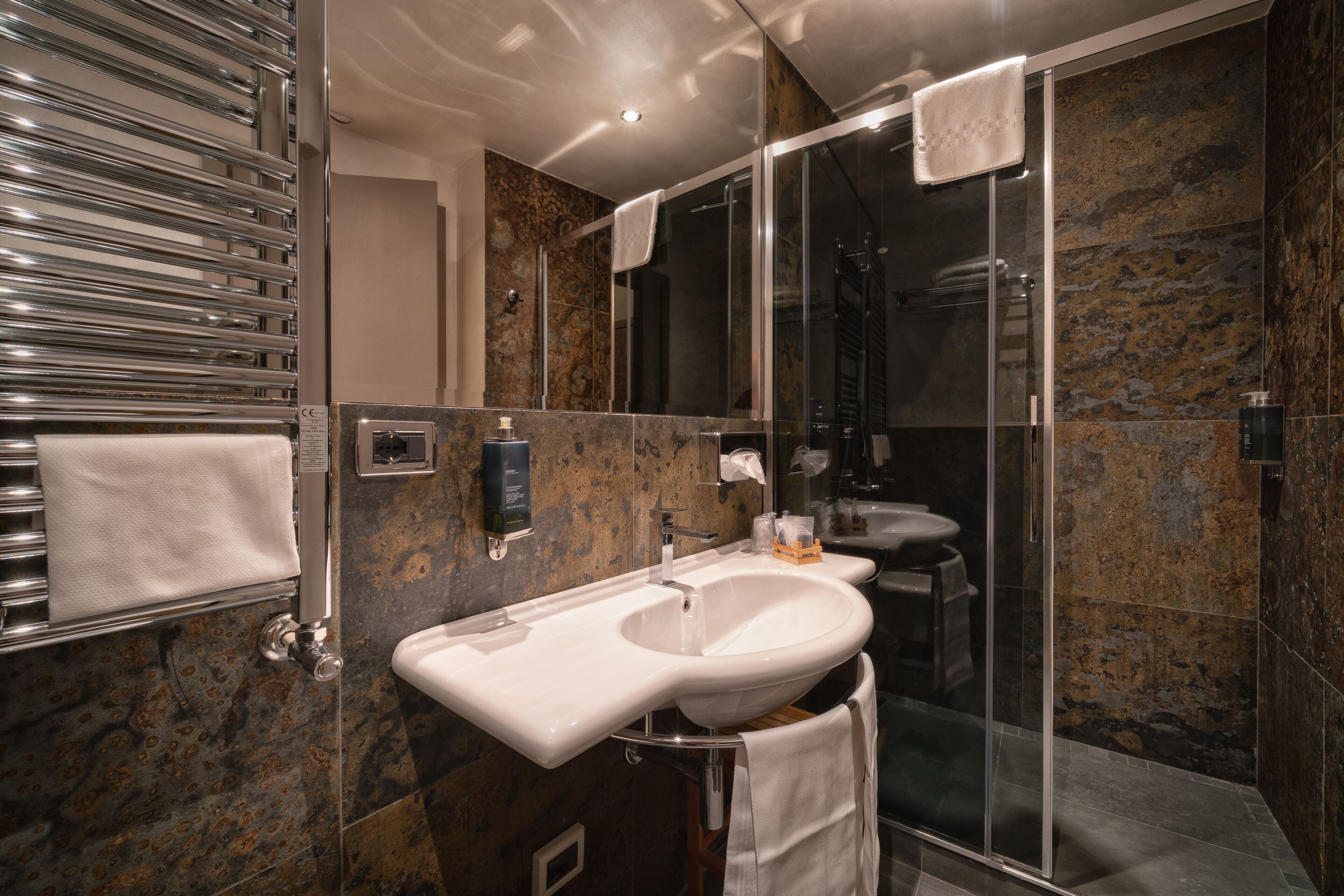 A modern bathroom with a glass-enclosed shower, a white sink, and a towel rack.