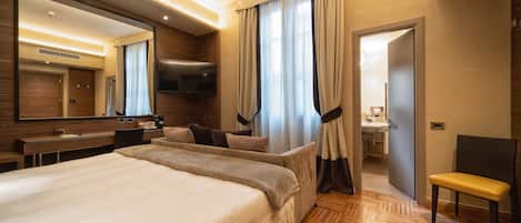 A hotel room with a large bed, a desk, a chair, a TV, and a bathroom visible through an open door.