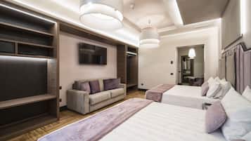A modern hotel room with two beds, a sofa, a TV, and built-in storage.
