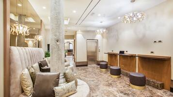 A lobby with a plush seating area, a reception desk, and a modern chandelier.
