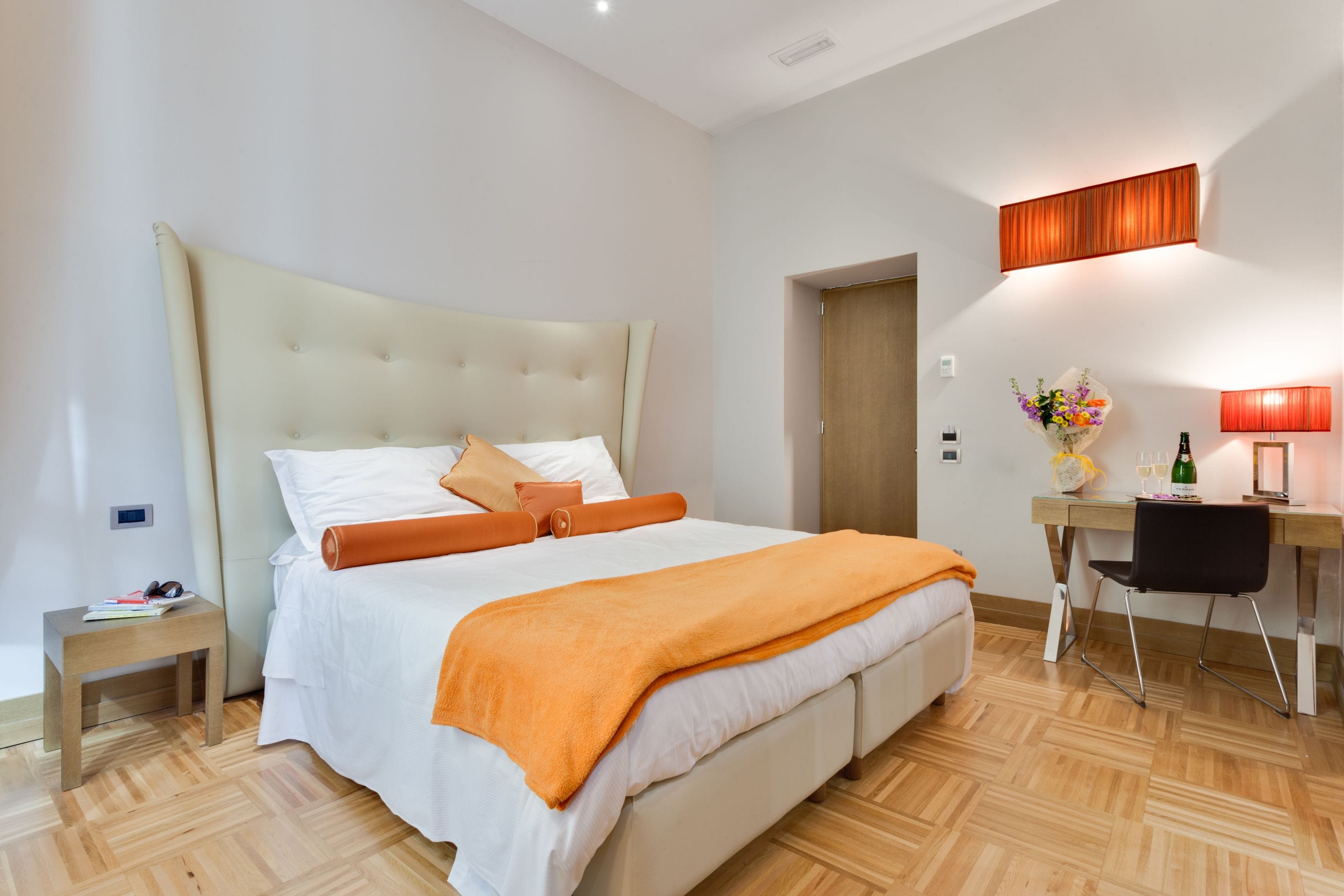 A modern bedroom with a large bed, a desk, and a chair.