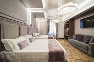 Una camera d'albergo con un letto grande, un divano, una TV e un pavimento in legno.