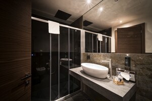 Un bagno moderno con cabina doccia in vetro, un lavandino capiente e uno specchio.