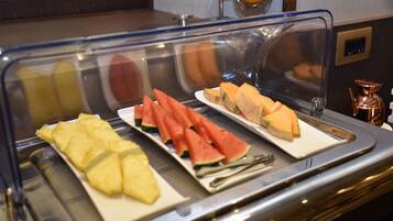 A buffet with sliced pineapple, watermelon, and sandwiches.