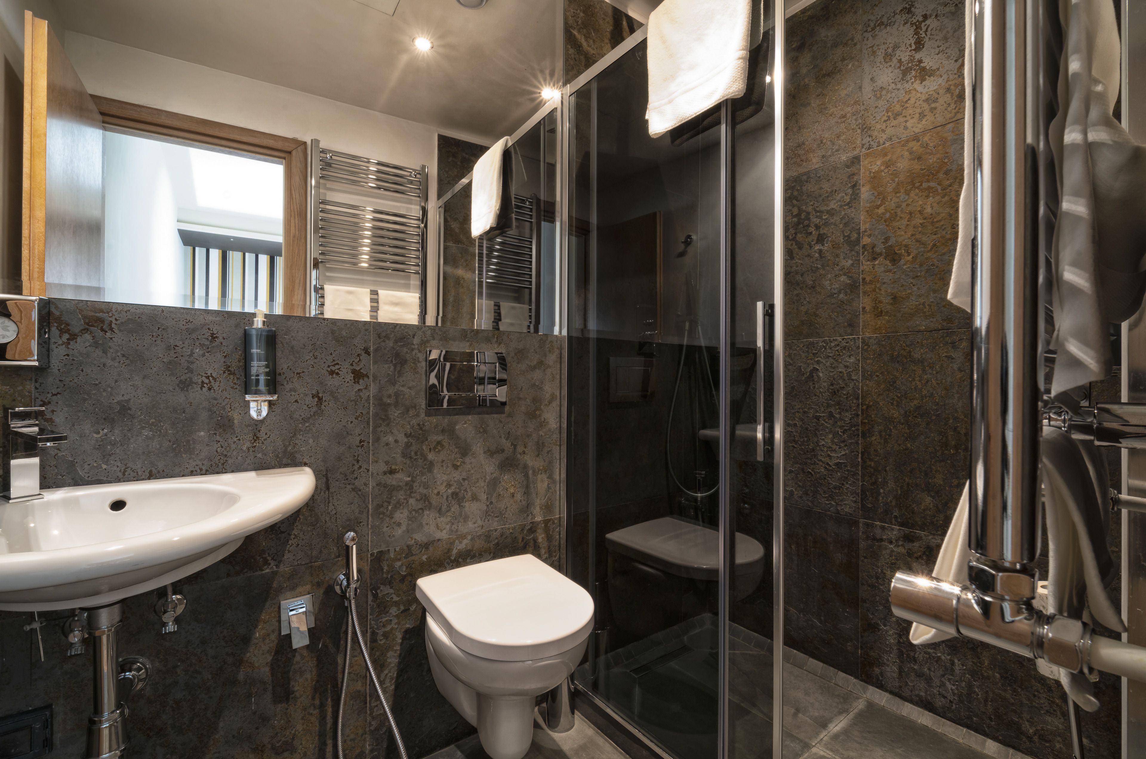 Un baño moderno con ducha de vidrio, lavamanos blanco y retrete.