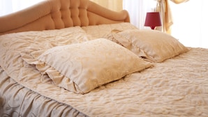 A bed with a tufted headboard and patterned bedding. - Hotel Victoria (Skopje)