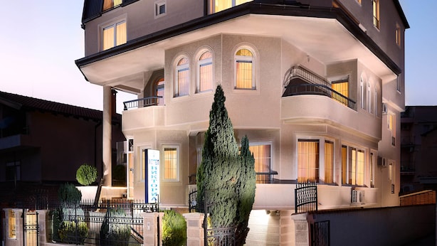 A multi-story building with a balcony, large windows, and a well-lit entrance. - Hotel Victoria (Skopje)