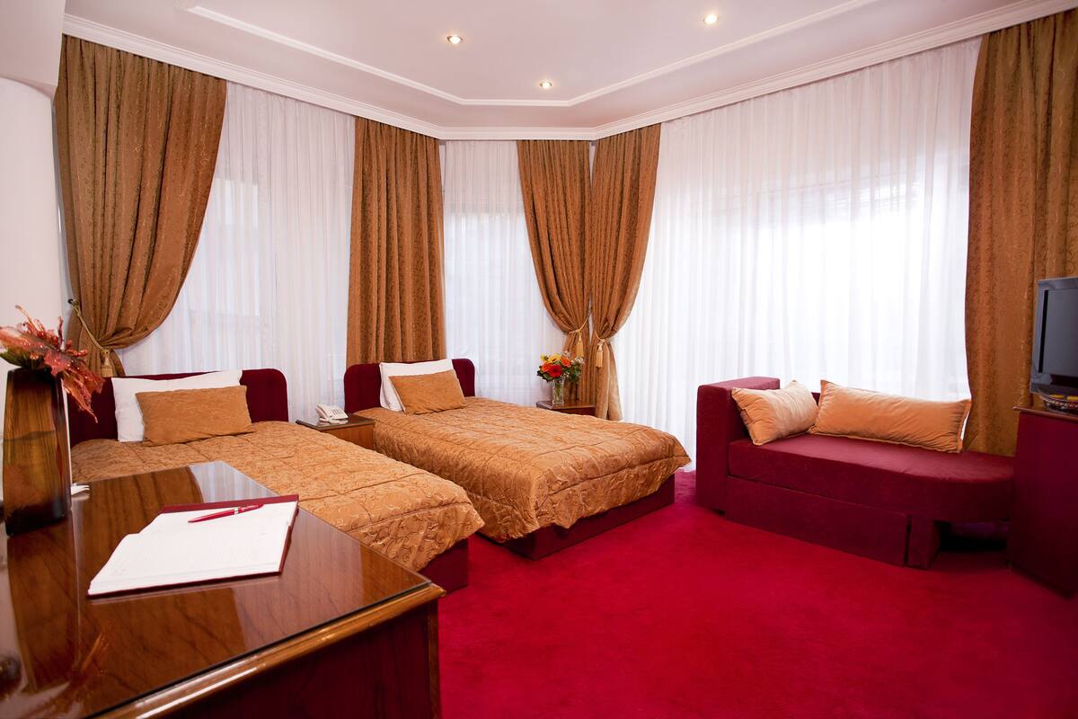 Una habitación de hotel con dos camas, un sofá, un televisor y un escritorio.