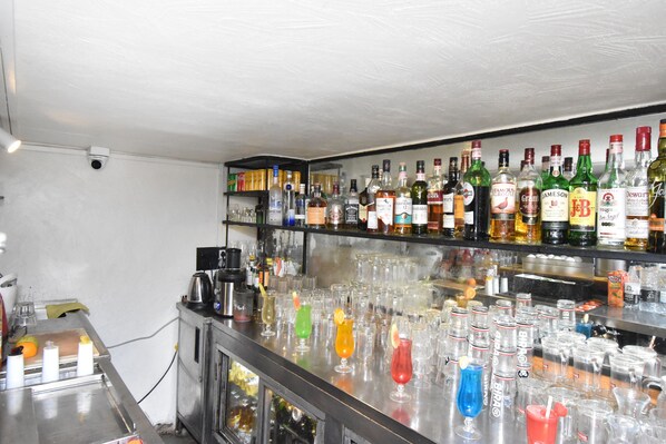 Una zona de bar con estantes llenos de botellas de licores y una variedad de copas.