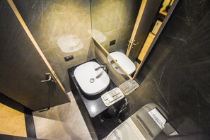A compact bathroom with a white sink, a toilet, and a mirror. - Kings International Juhu (Mumbai)