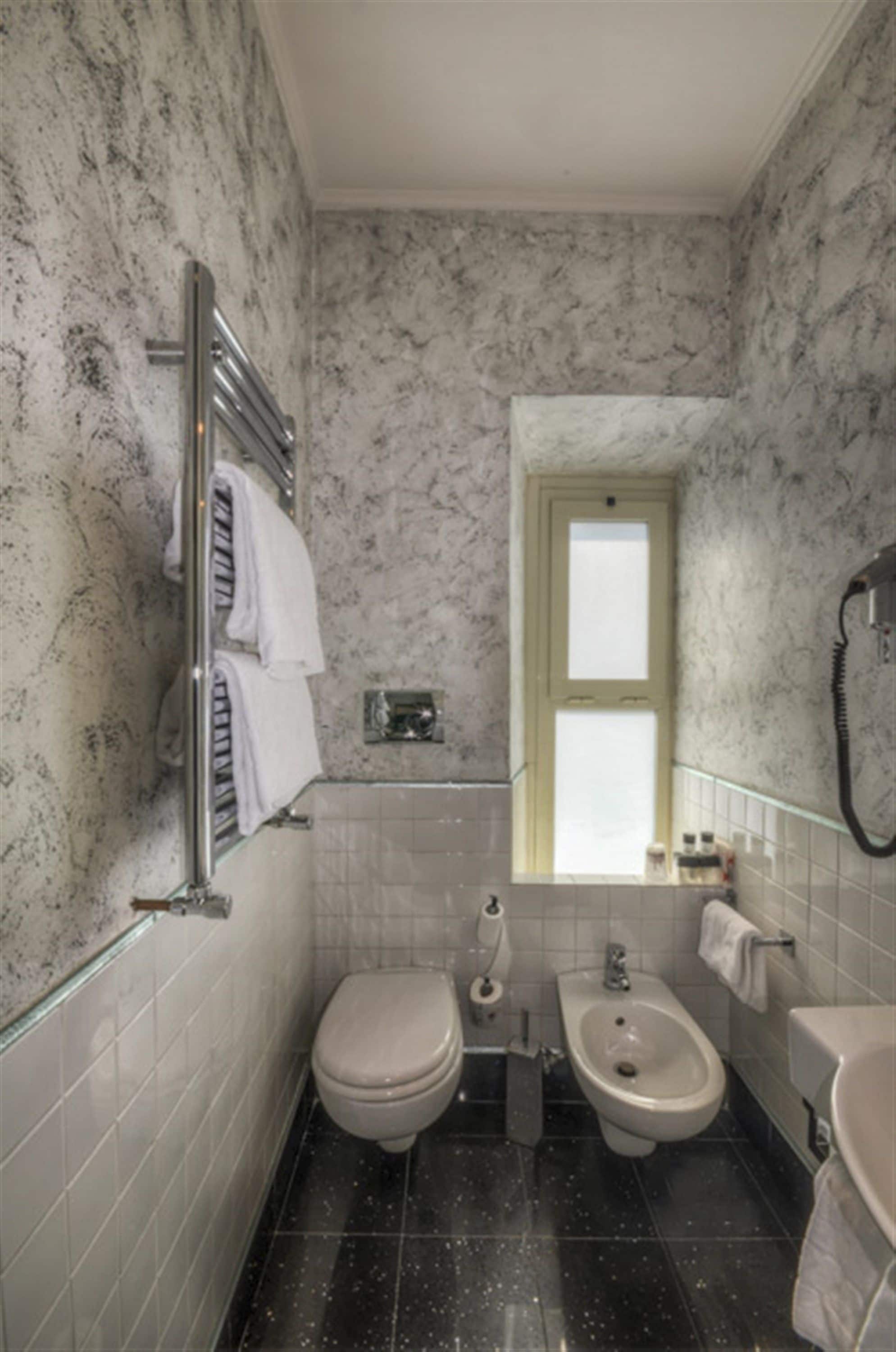A bathroom with a toilet, bidet, and sink.