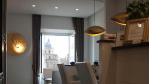 Ein modernes Hotelzimmer mit Essbereich, einem großen Fenster und Blick auf die Stadt sowie einem gemusterten Teppich.