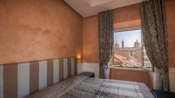 Une chambre d’hôtel avec un grand lit, une table de chevet et une fenêtre avec des rideaux.