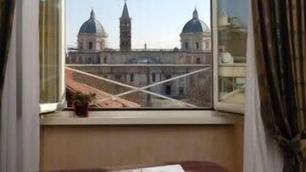 Ein Zimmer mit Bett, Fenster und Blick auf ein Gebäude mit Kuppeln und Türmen.