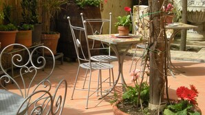 A patio with metal chairs and a table, surrounded by potted plants and a decorative urn. - L'Argine Fiorito (Atrani)
