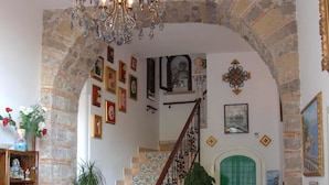 A spacious living area with a staircase, a chandelier, and a green door. - L'Argine Fiorito (Atrani)
