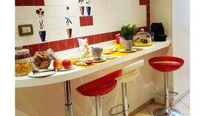 A kitchen with a white countertop, red and white tiles, and a potted plant. - B&B Emozioni Romane (Rome)