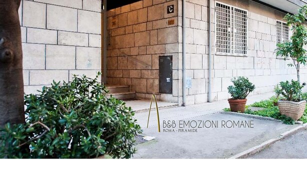 A building entrance with a stone facade, a metal gate, and potted plants. - B&B Emozioni Romane (Rome)