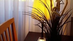 A room with a chair, a table, a lamp, and a plant near a window with sheer curtains. - B&B Emozioni Romane (Rome)