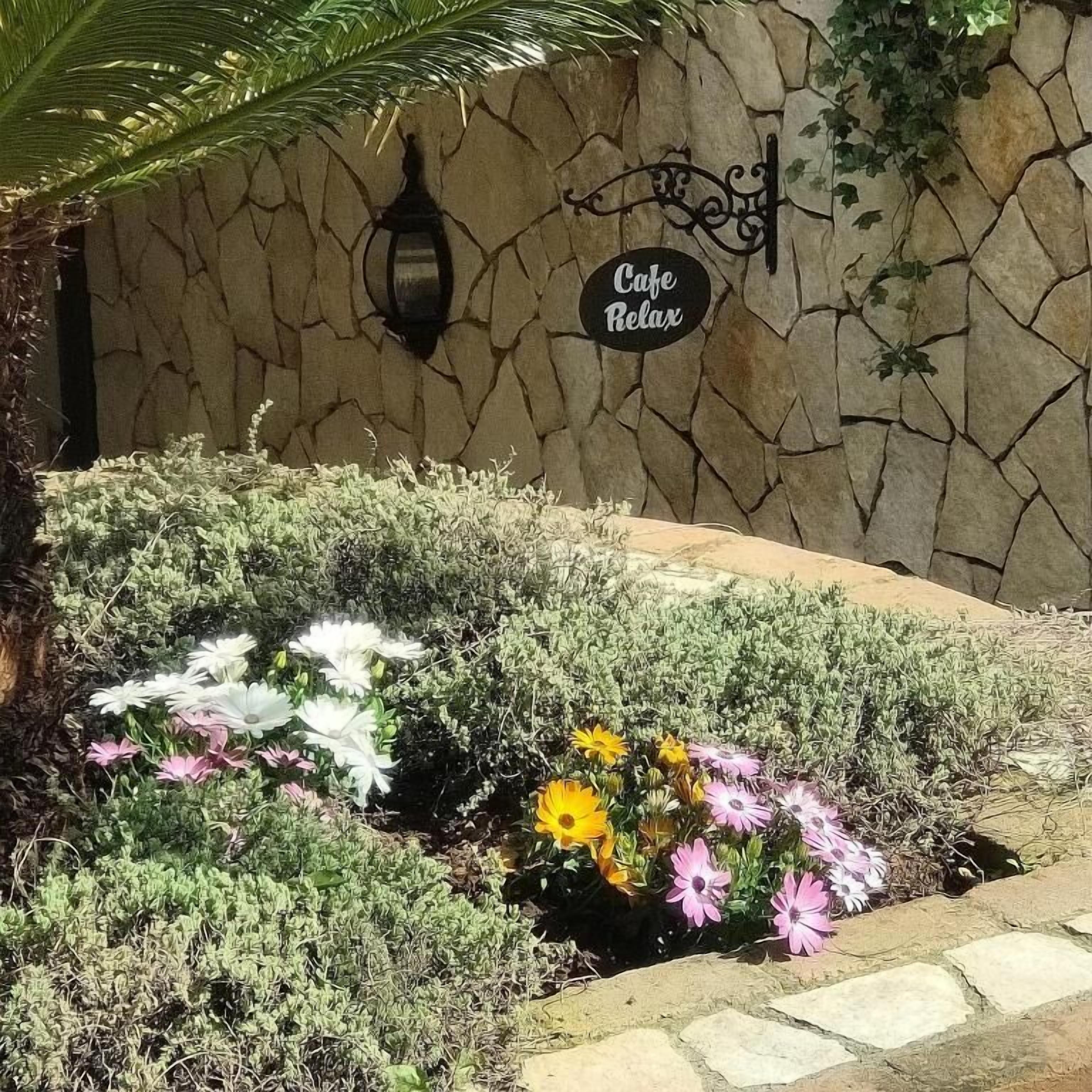 A stone wall with a sign that reads 'Cafe Relax.'
