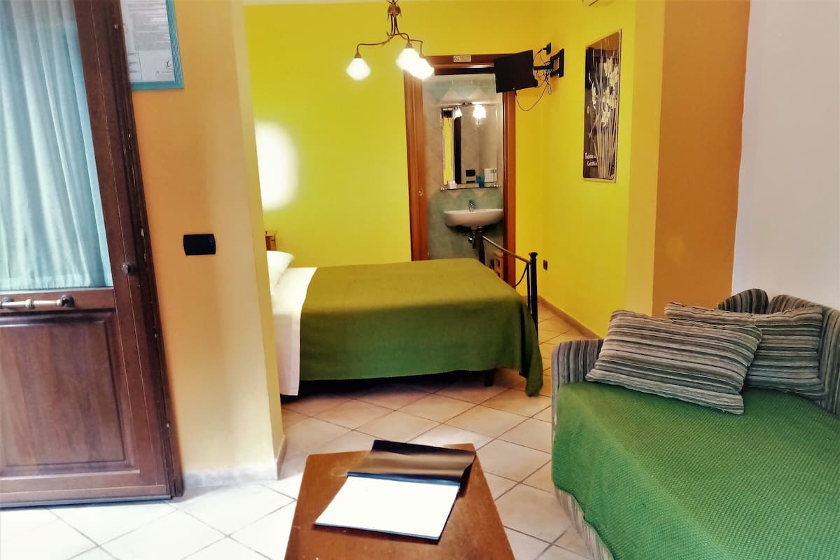A room with two beds, a wooden table, a sink, and a mirror.