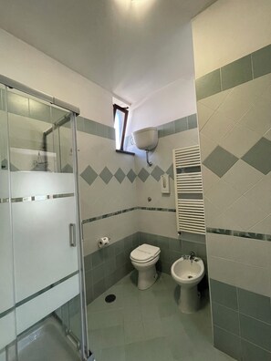 A bathroom with a glass shower enclosure, a toilet, a bidet, and a wall-mounted sink. - Albergo Pace (Pompei)