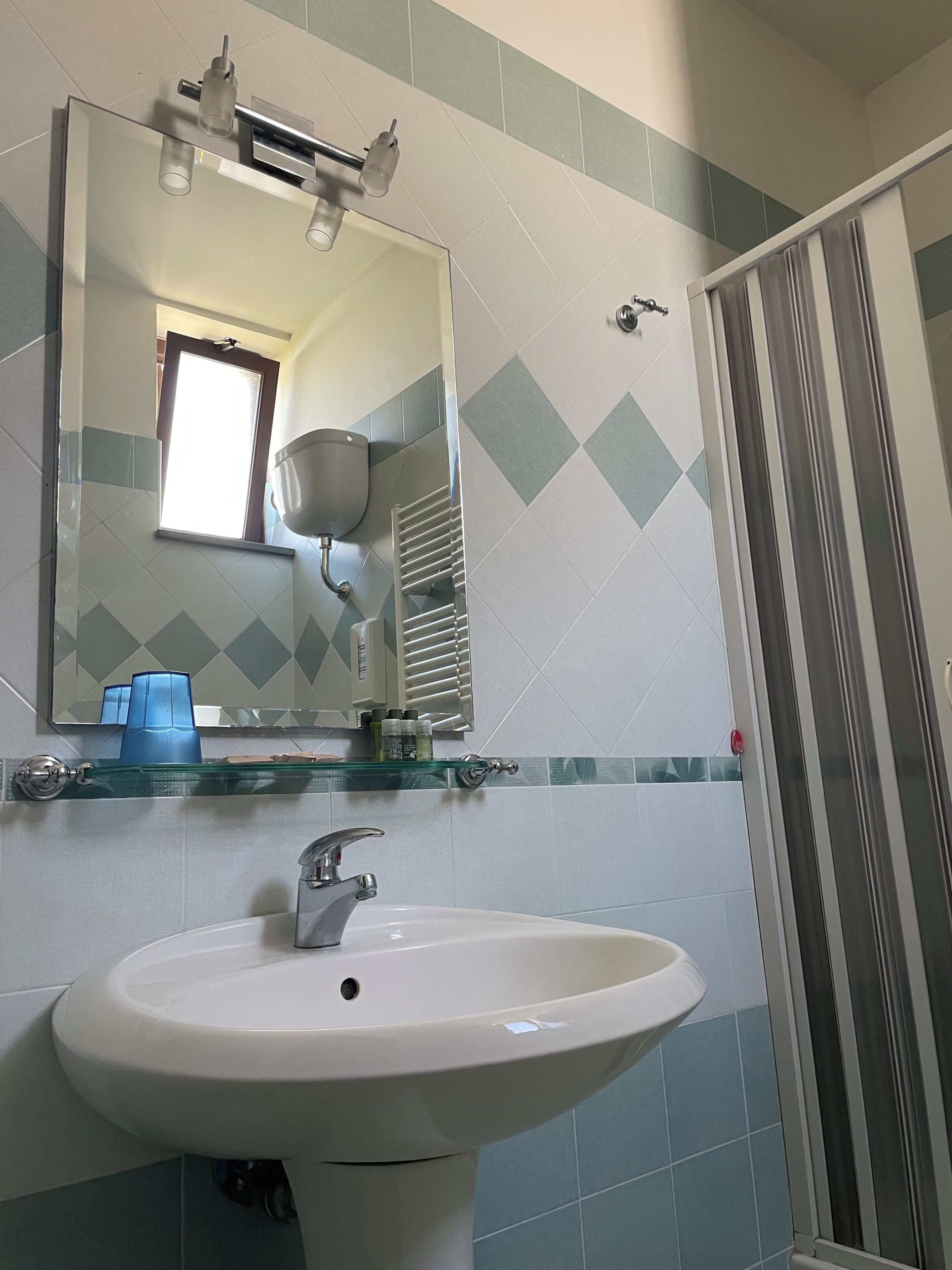 A bathroom with a white sink, a mirror, and a shower area.