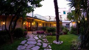 A courtyard with a stone pathway leading to a building with a balcony. - Albergo Pace (Pompei)