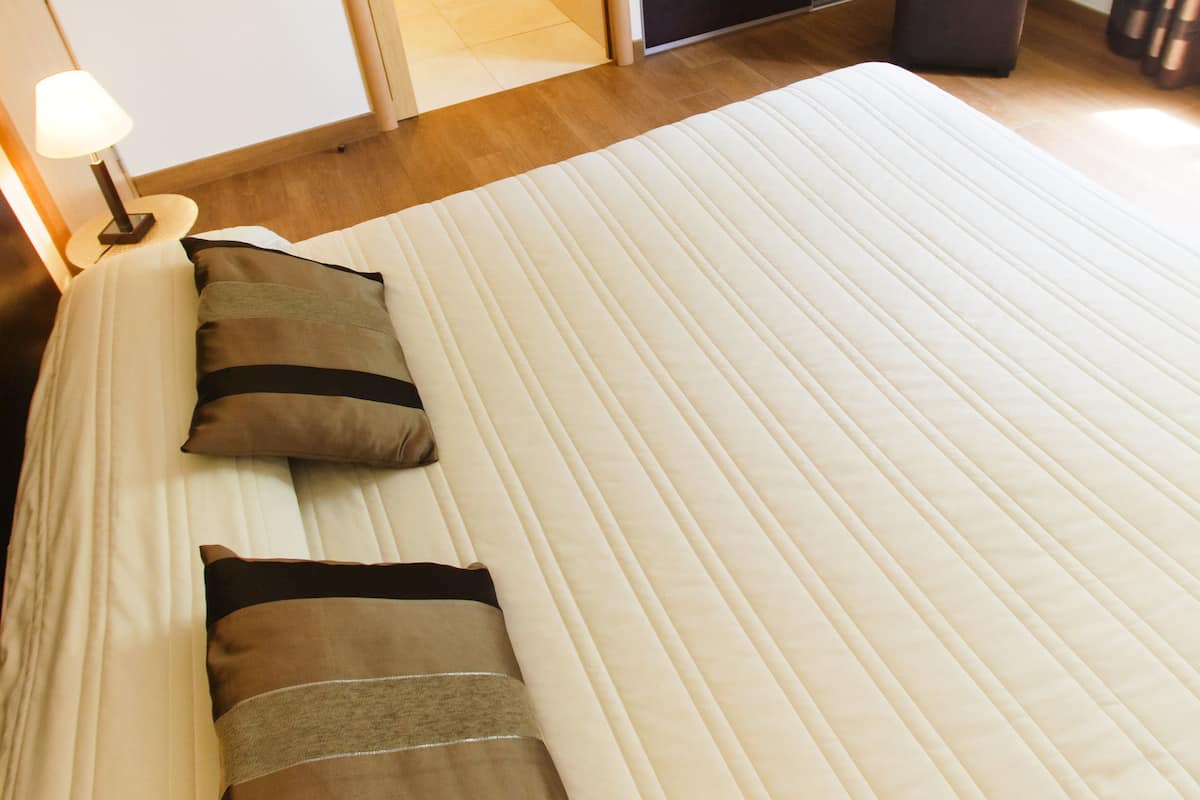 A neatly made bed with pillows and a bedside lamp in a hotel room.